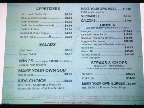 The tavern's printed menu board photographed on the wall, listing appetizers, salads, dinners and steaks